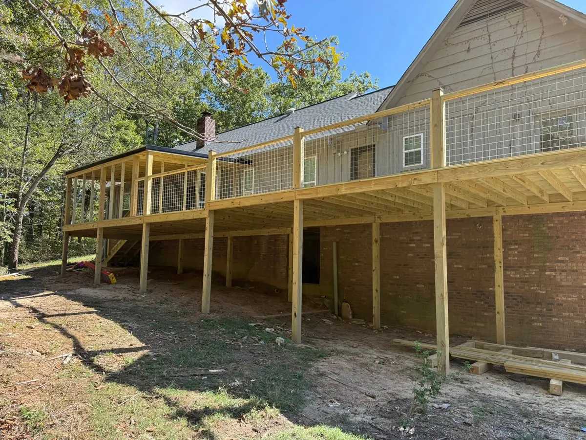 Elevated wood deck with railing on the back of a brick home