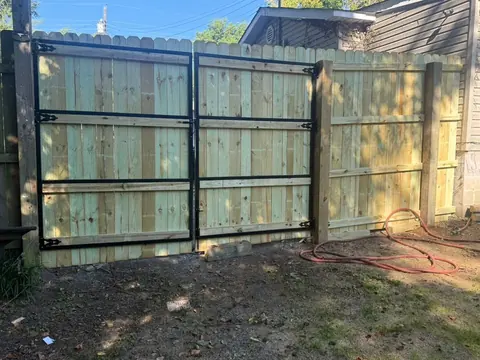 Wide wood gate with a black steel frame set into a privacy fence