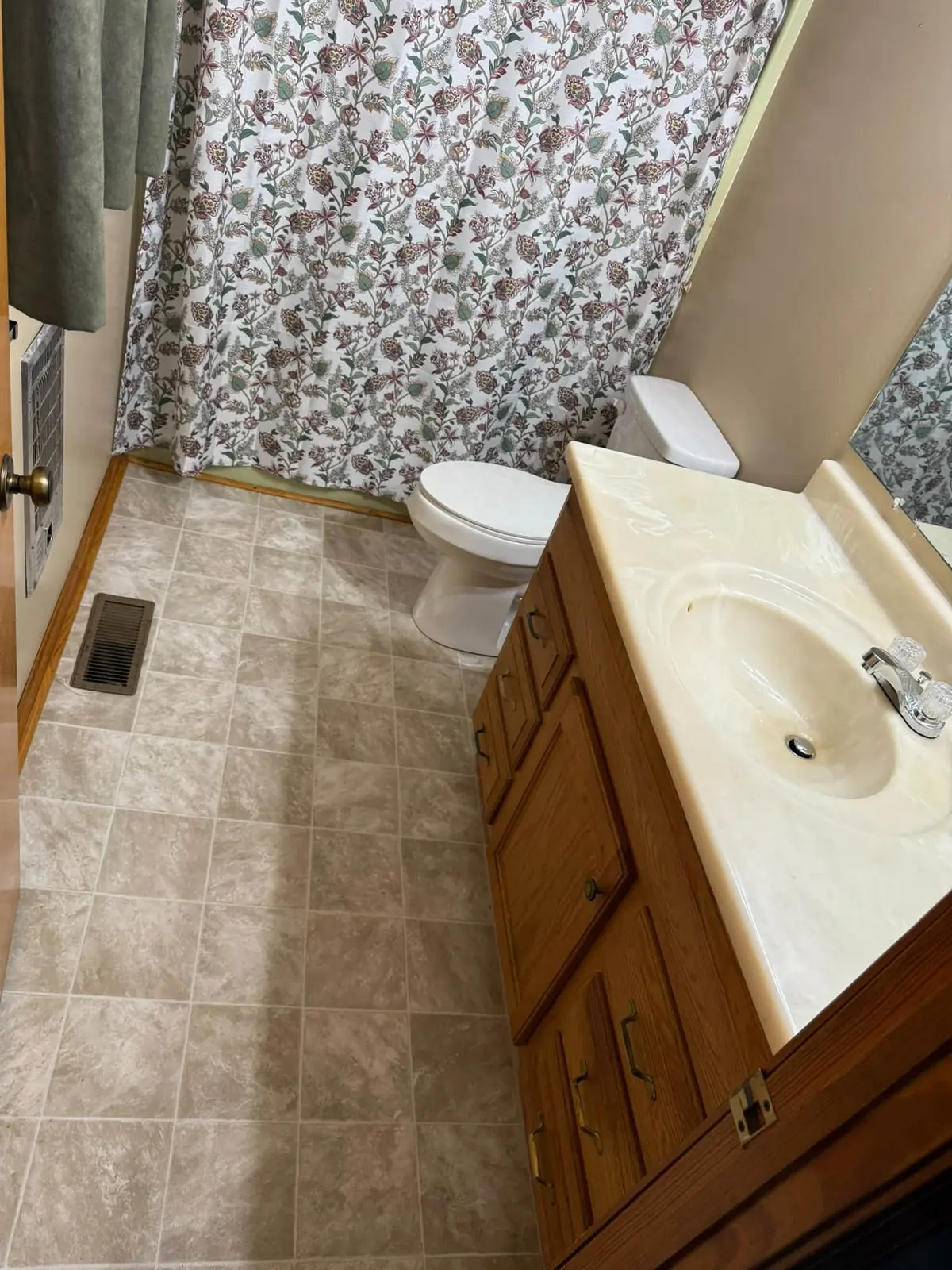 Bathroom with new tile-pattern flooring and a wood vanity