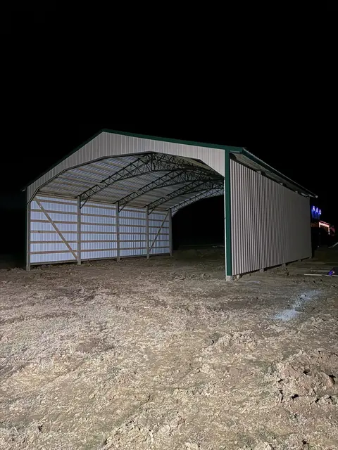 Open-ended pole building with metal walls and roof photographed at night