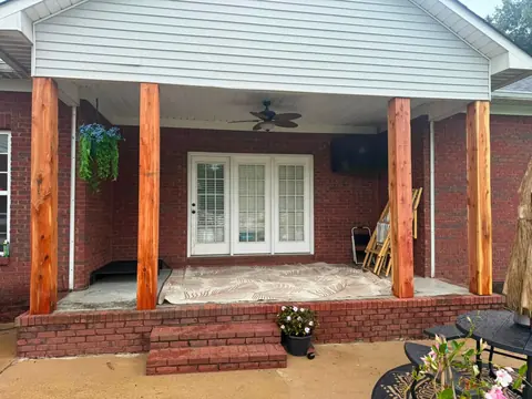 Covered brick-front porch with four cedar posts and a ceiling fan