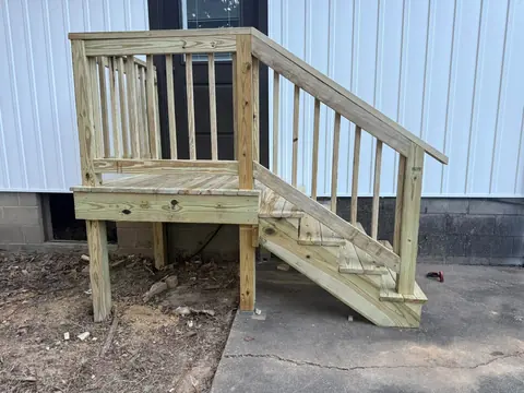 New treated-lumber entry stairs and landing beside a metal building